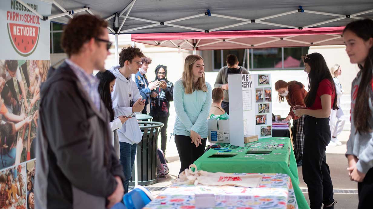 Students chat with each other on the Student Union Plaza over tables that promote different student organizations. 