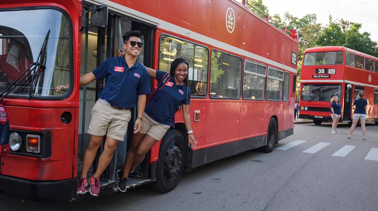Two Ole Miss orientation leaders pose next to one of Oxford's famous red, double-decker buses.