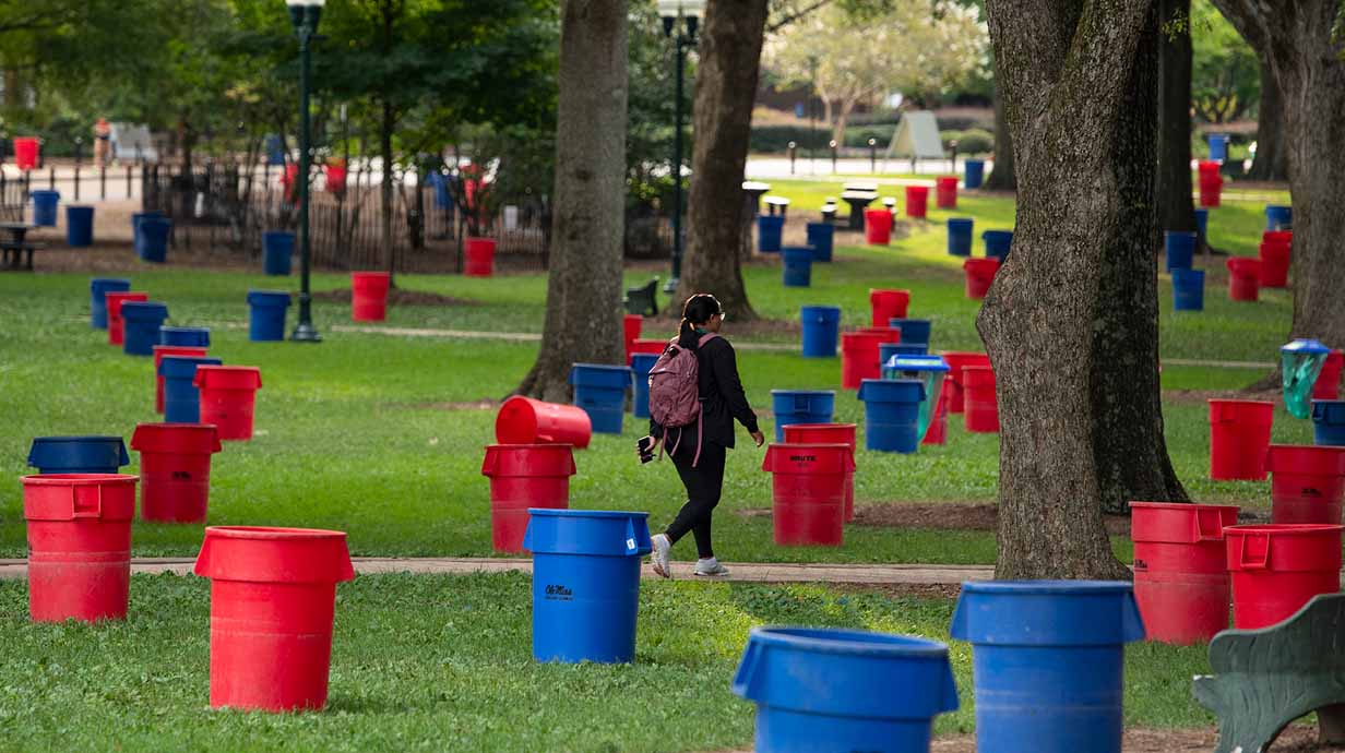 A student walks through the Grove surrounded by a sea of trash cans on Trash Can Friday.